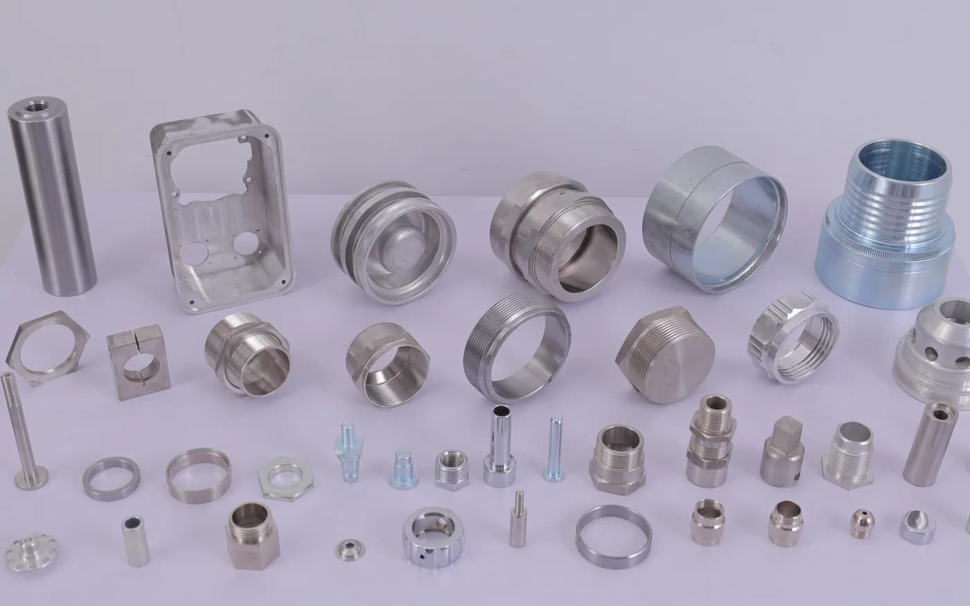 Stainless and aluminium turned and milled components — shafts, rings, a plated threaded coupling, a machined plate, pins and washers